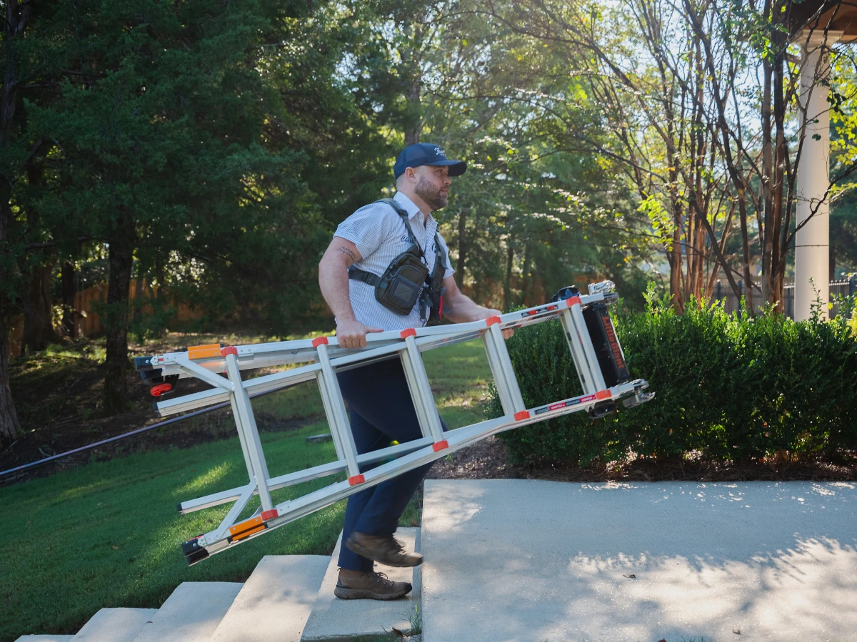 residential christmas light installer carrying ladder